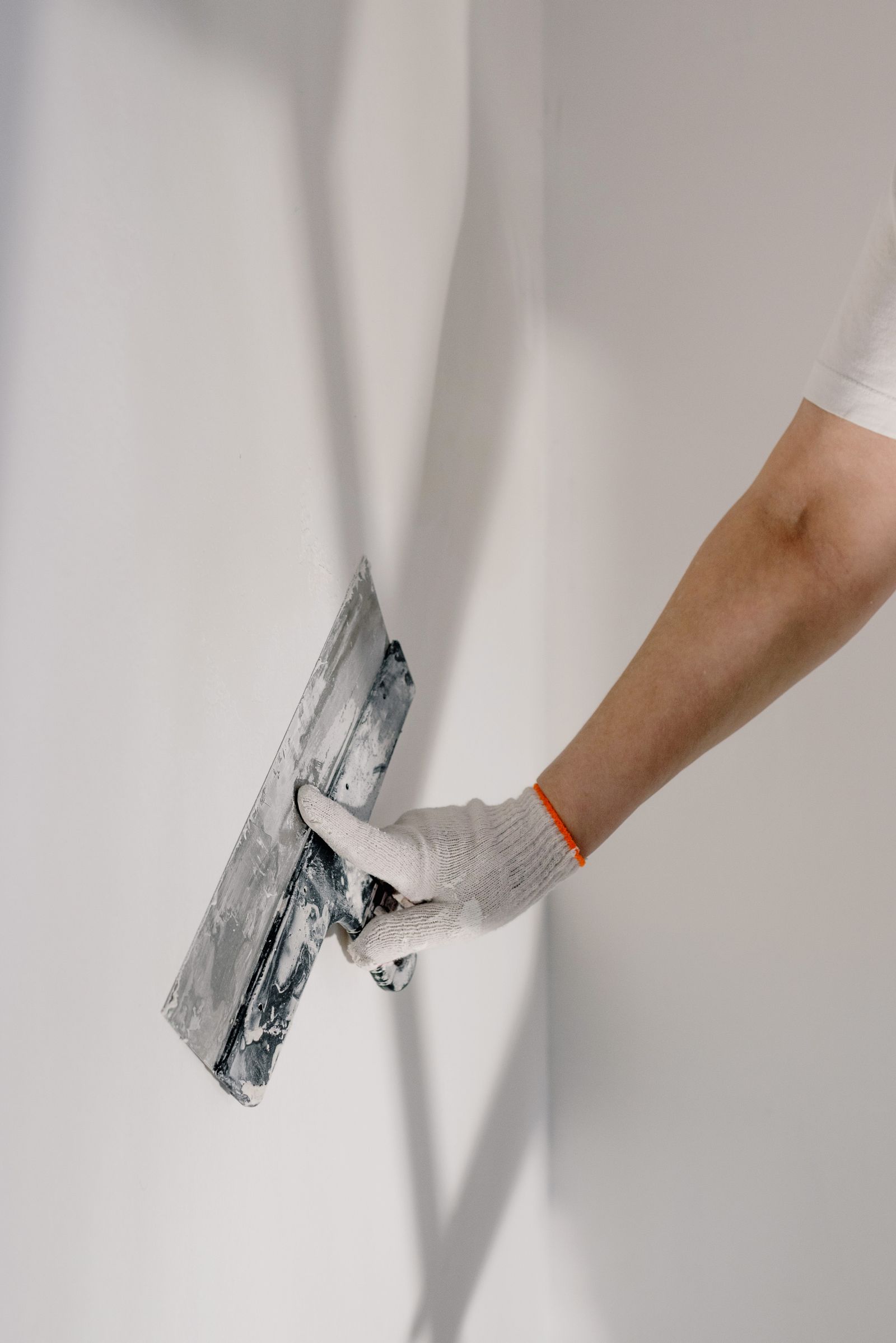 Een stucwerker zet een wand glad met een spaan